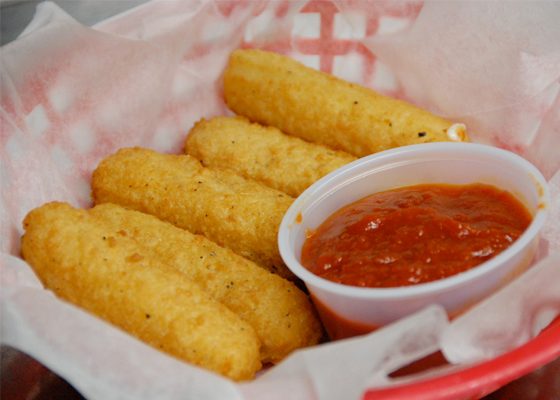 Mozzarella sticks in a paper-lined basket with a cup of marinara.