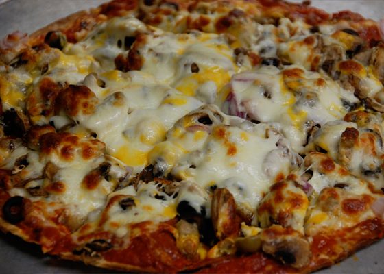 A whole pizza with browned cheese, mushrooms and onions.